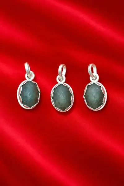 Navapashanam Pendant with a dark grey stone and silver-fitted frame, displayed on a vibrant red background.