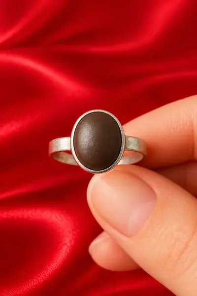 Front view of the Navapashanam Healing Ring with an oval brown bead and polished silver frame