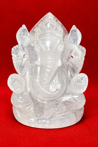 White Sphatik Ganesh Ji idol displayed on a vibrant red background, highlighting its clear crystal appearance and detailed carving.