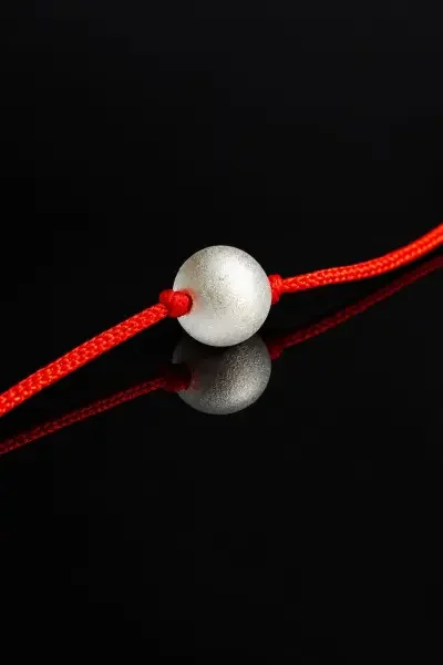 Close-up of 5 Gram Parad Gutika placed on a glossy black surface, highlighting its metallic finish and traditional red thread.