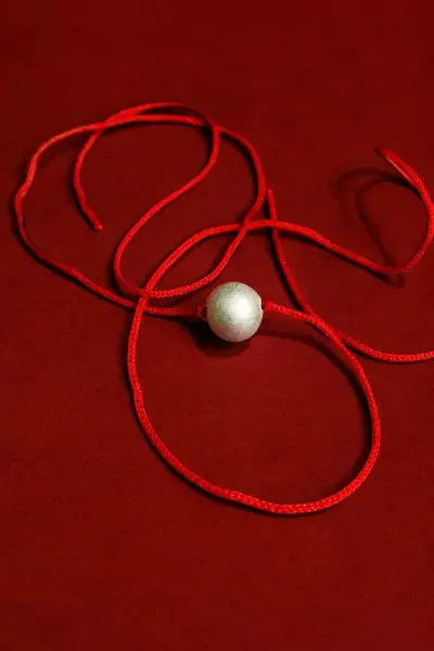 Parad Gutika with red sacred thread displayed on a rich red background, ideal for showcasing its devotional and spiritual character.