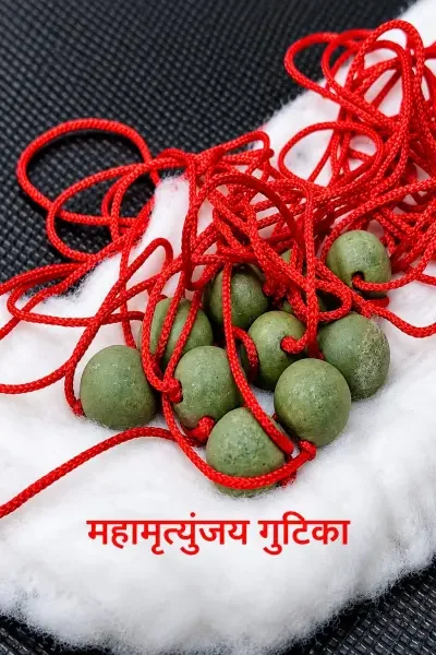 Multiple MahaMrityunjay Gutika beads with red sacred threads arranged on white fabric, showcasing the traditional devotional product and its natural green appea
