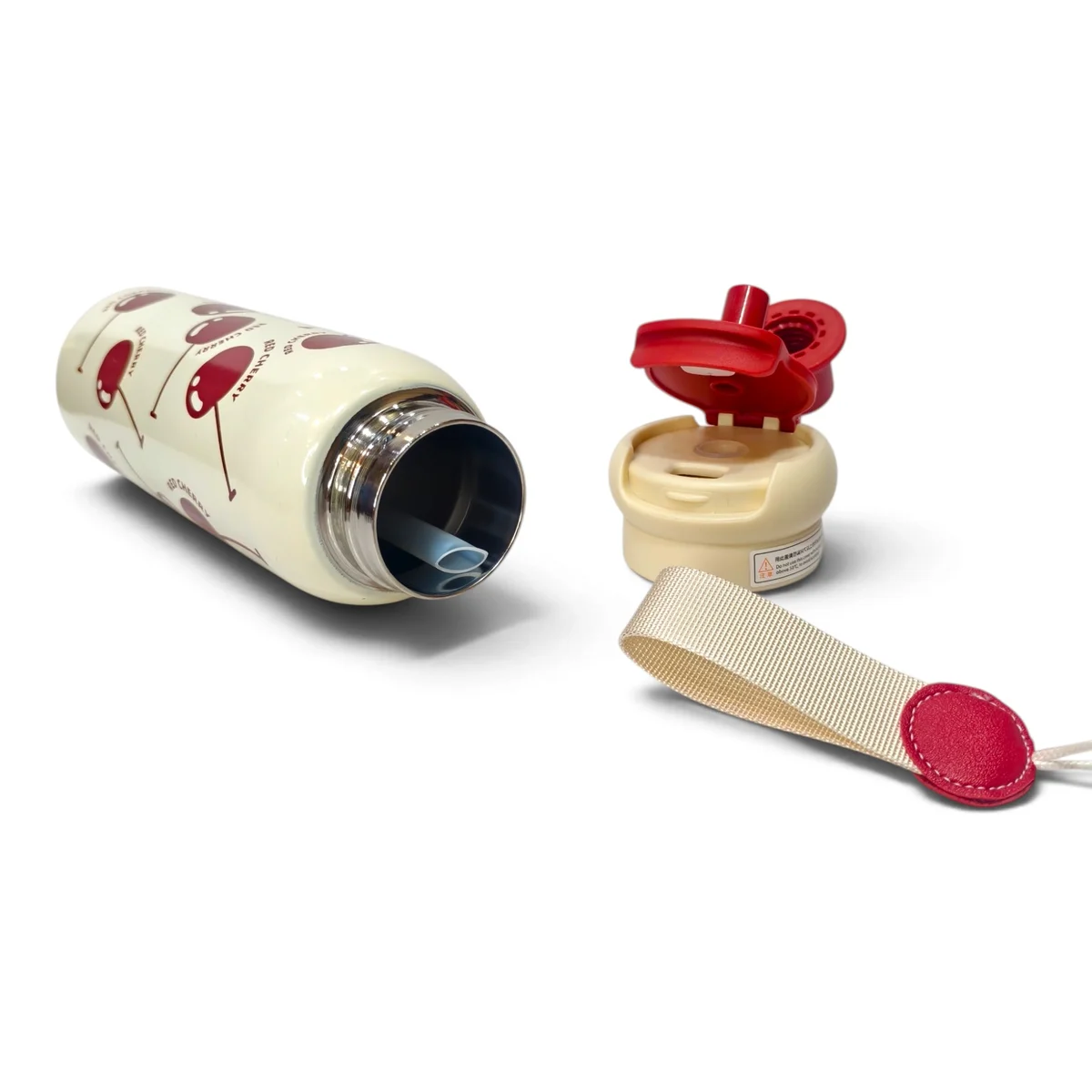 Detailed product image showing the cherry print kids water bottle lying horizontally with its lid and carry strap separated from the bottle. The open bottle rev